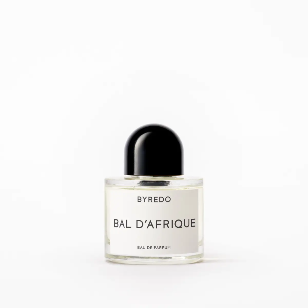 A bottle of Byredo Bal d'Afrique Eau de Parfum featuring its signature minimalist round white label and black domed cap. The perfume is known for its vibrant blend of African marigold, bergamot, and cedarwood.