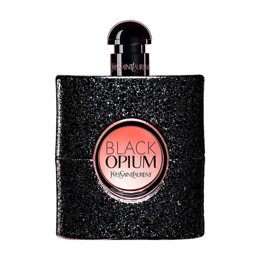 The shimmering black glitter bottle of YSL Black Opium Eau de Parfum with its central pink-toned porthole, styled in a moody, late-night setting to highlight its coffee and vanilla notes.