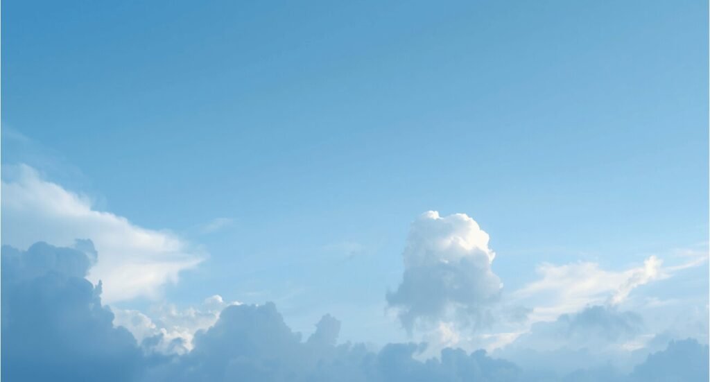 Minimalist blue sky with fluffy white clouds aesthetic wallpaper.